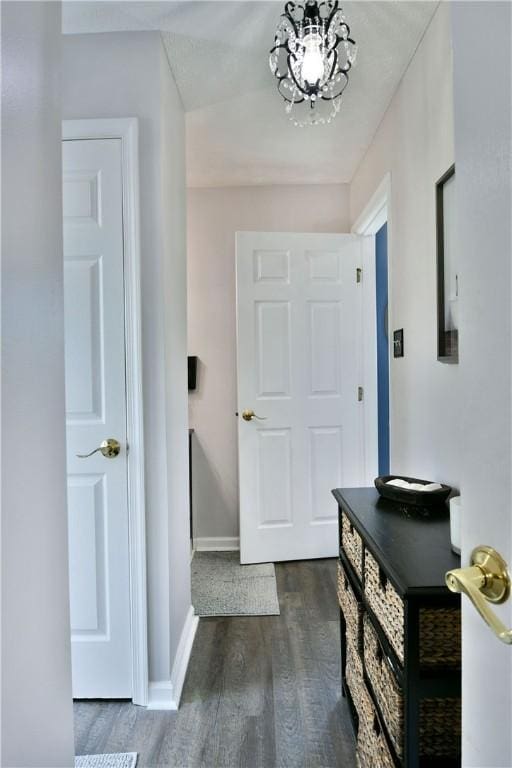 entrance foyer with dark wood-style floors, baseboards, and an inviting chandelier