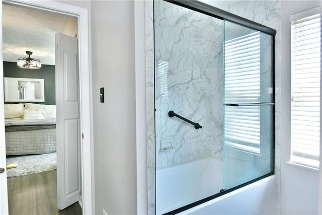 full bathroom with bath / shower combo with glass door, wood finished floors, and a wealth of natural light