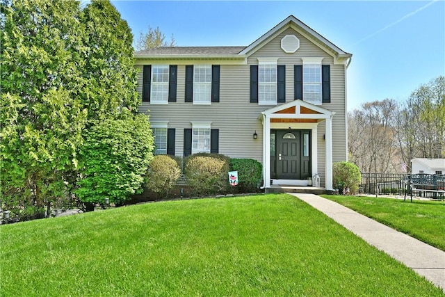 colonial home with a front lawn and fence