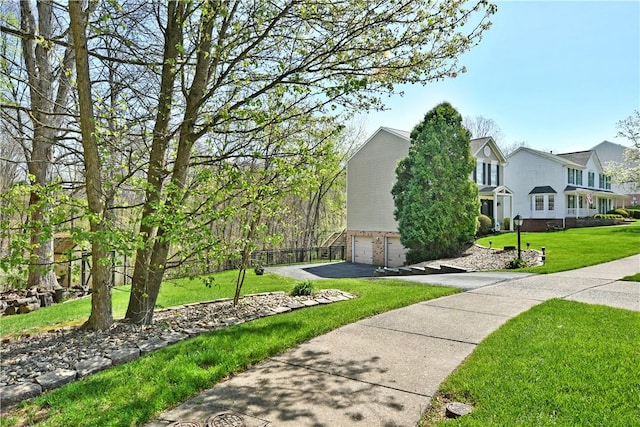 view of side of property with a lawn, aphalt driveway, brick siding, and a garage