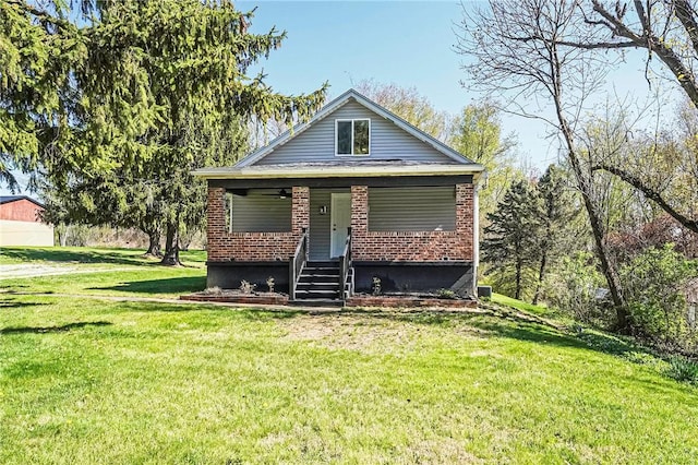 bungalow-style home with covered porch, a front yard, and brick siding