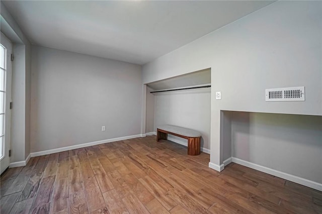 unfurnished bedroom with wood finished floors, visible vents, baseboards, and a closet