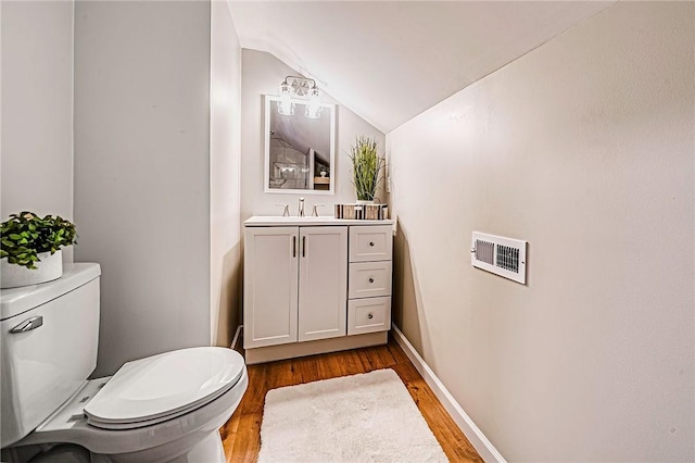 bathroom with visible vents, wood finished floors, toilet, and lofted ceiling