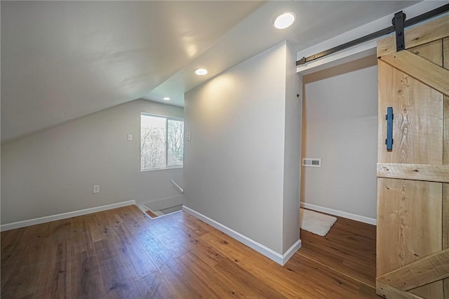 bonus room featuring lofted ceiling, a barn door, baseboards, recessed lighting, and wood finished floors