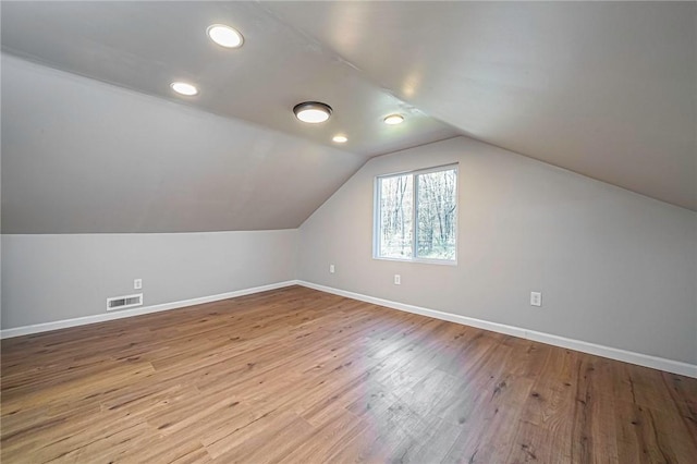 bonus room with lofted ceiling, wood finished floors, visible vents, and baseboards