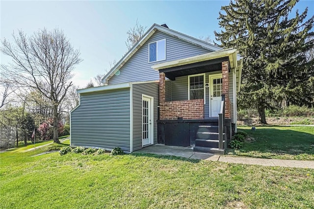 rear view of property with brick siding, a porch, and a yard