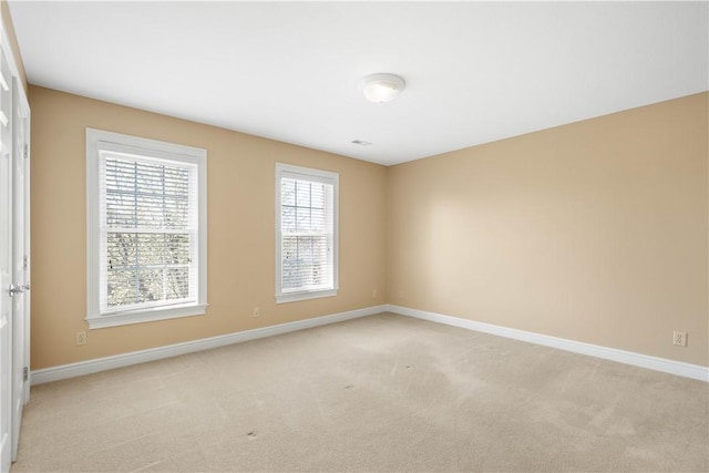 unfurnished room featuring light colored carpet and baseboards