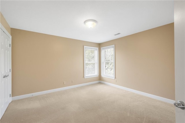 empty room with visible vents, light carpet, and baseboards