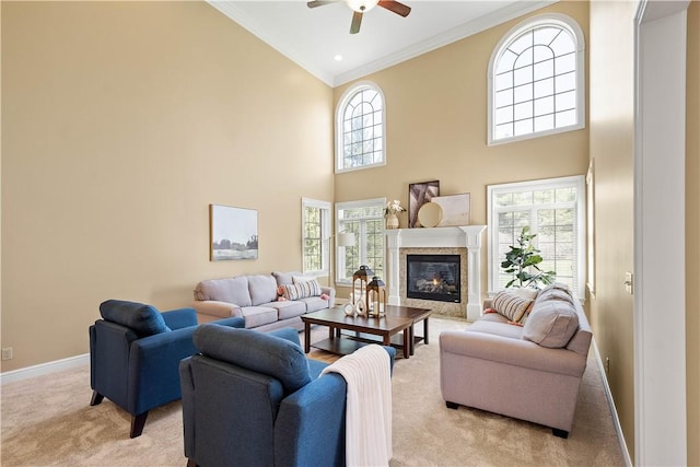 living area with ornamental molding, a towering ceiling, ceiling fan, and light colored carpet