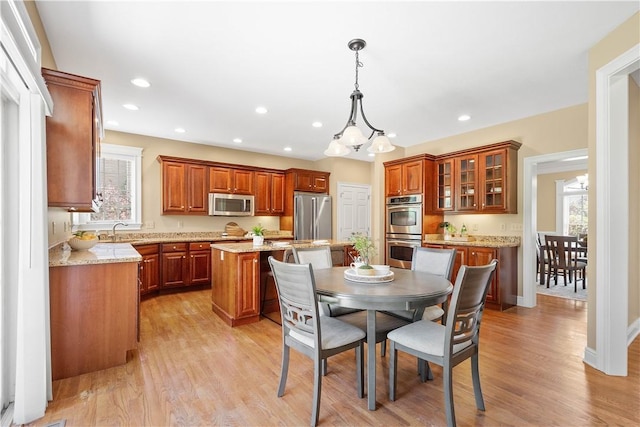 kitchen with a center island, stainless steel appliances, brown cabinets, and plenty of natural light