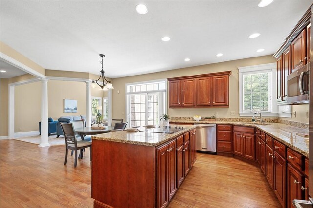 kitchen featuring decorative columns, stainless steel appliances, light stone countertops, and a sink