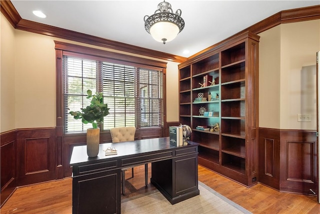 home office with ornamental molding, a wainscoted wall, and light wood-style flooring