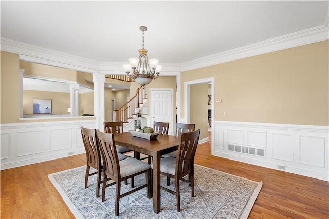dining space featuring visible vents, ornamental molding, a notable chandelier, and light wood-style flooring