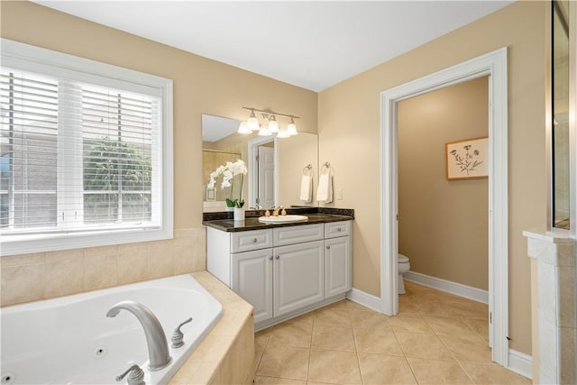 bathroom with tile patterned floors, toilet, vanity, baseboards, and a jetted tub