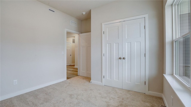 unfurnished bedroom with carpet flooring, a closet, visible vents, and baseboards