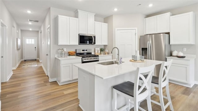 3026 Audrey Dr, Hempfield Twp Wml, PA 15601 - kitchen with stainless steel appliances, a sink, a breakfast bar, a center island with sink, and light wood-type flooring