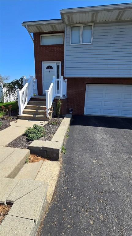 view of front of house with a garage, aphalt driveway, and brick siding