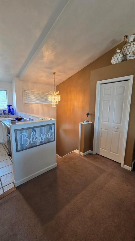interior space featuring a notable chandelier, vaulted ceiling, and carpet flooring