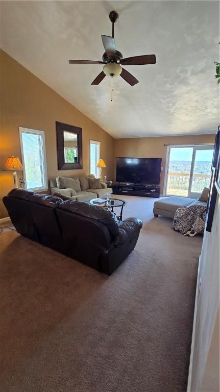 carpeted living area with ceiling fan and vaulted ceiling