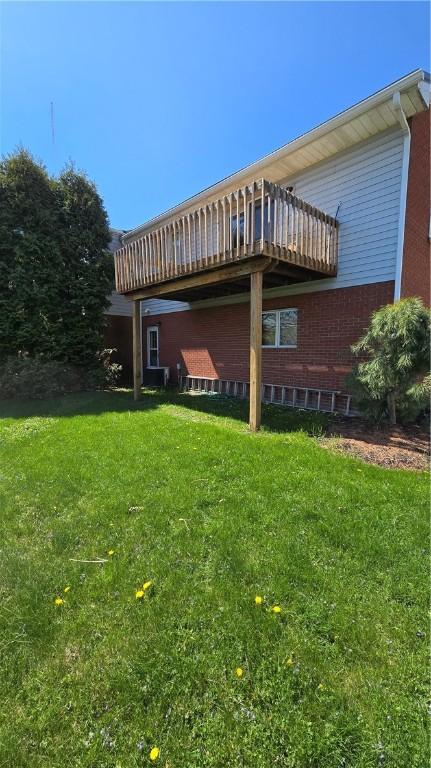 rear view of property featuring a deck, brick siding, and a yard