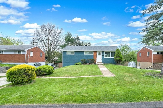 view of front of property featuring a storage unit, brick siding, and a front lawn