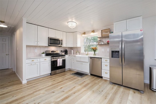 kitchen featuring white cabinetry, light wood-type flooring, appliances with stainless steel finishes, and light countertops