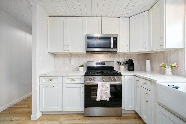 kitchen featuring white cabinets, stainless steel appliances, and backsplash