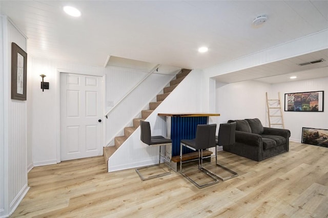 living area with stairway, wood finished floors, visible vents, and baseboards