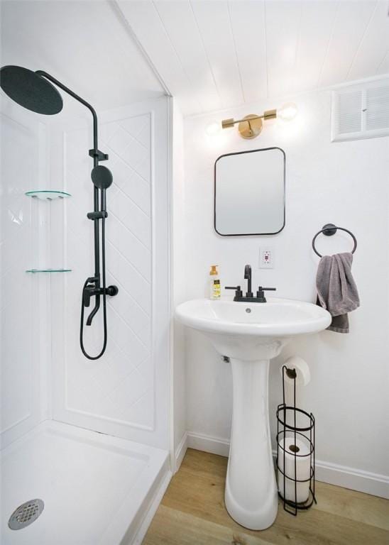 full bathroom with baseboards, wood finished floors, and a shower stall