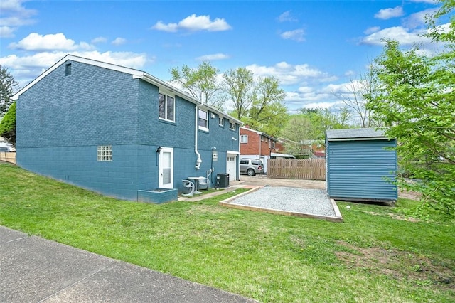 back of property with an outdoor structure, a storage shed, a lawn, central AC, and fence