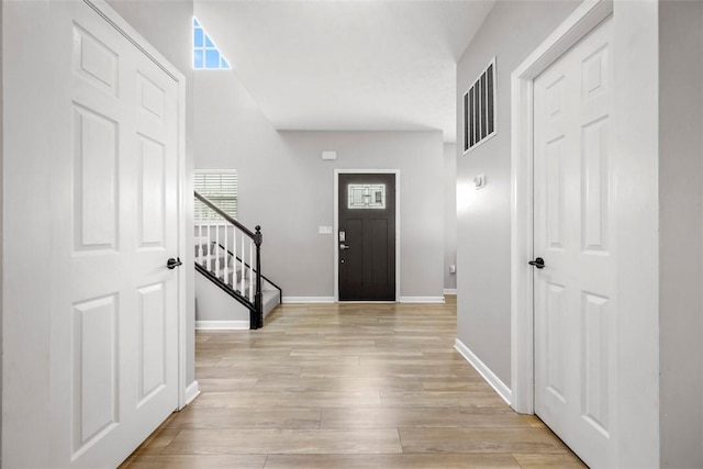 foyer entrance with stairway, visible vents, light wood-style flooring, and baseboards