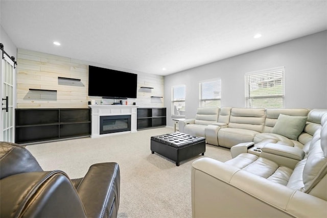 living area with recessed lighting, a glass covered fireplace, a barn door, and carpet