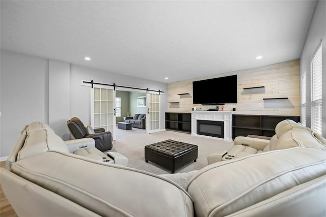 living room with a barn door, recessed lighting, wooden walls, and plenty of natural light