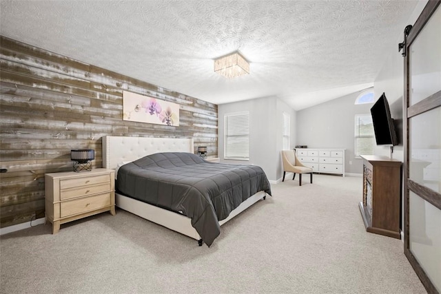 carpeted bedroom featuring a barn door, wood walls, baseboards, a textured ceiling, and lofted ceiling