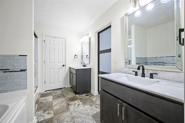 bathroom featuring baseboards, two vanities, a shower stall, and a sink