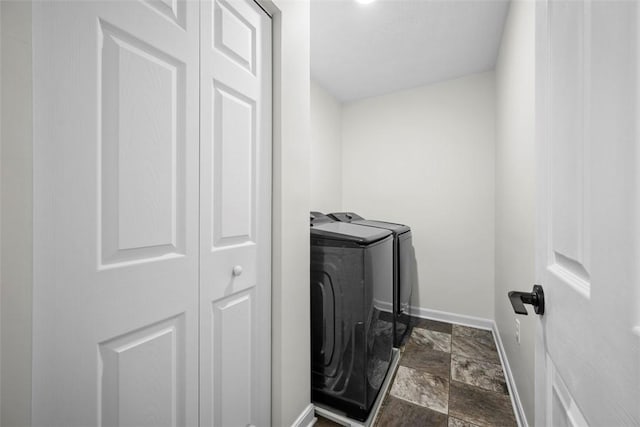 washroom featuring stone finish flooring, separate washer and dryer, laundry area, and baseboards