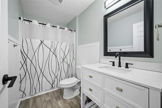 bathroom featuring a textured ceiling, wood finished floors, toilet, and vanity