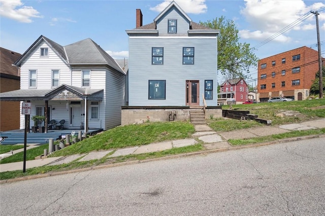 view of front of house featuring a chimney and covered porch