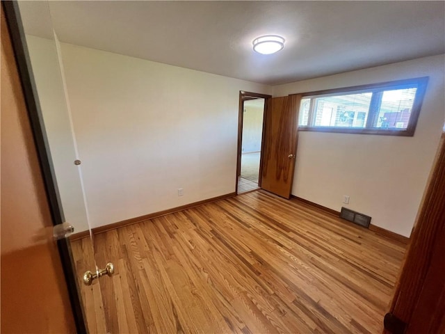 spare room featuring baseboards, visible vents, and light wood-style flooring