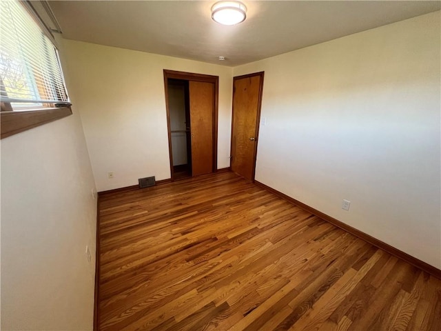 spare room with wood finished floors, visible vents, and baseboards