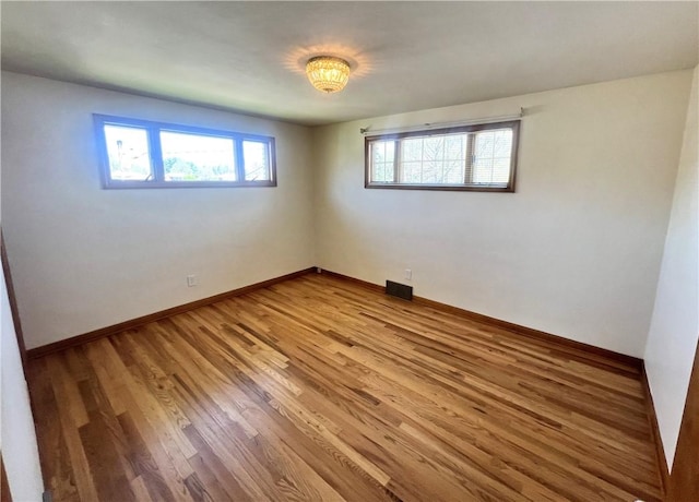 empty room featuring visible vents, baseboards, and light wood-type flooring