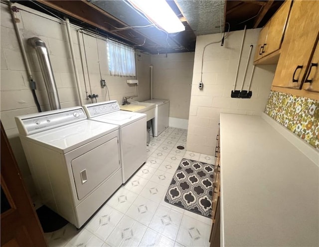 laundry area with concrete block wall, washing machine and dryer, cabinet space, and a sink