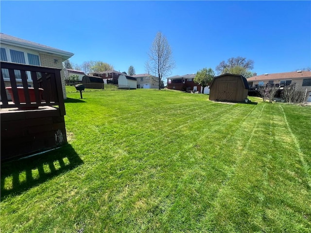 view of yard featuring a shed, an outbuilding, and a residential view