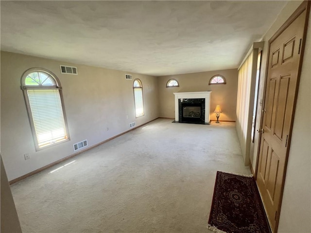 unfurnished living room with a premium fireplace, visible vents, and a wealth of natural light
