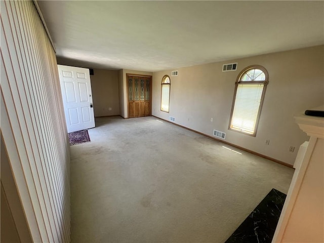 unfurnished living room featuring visible vents, carpet floors, and baseboards