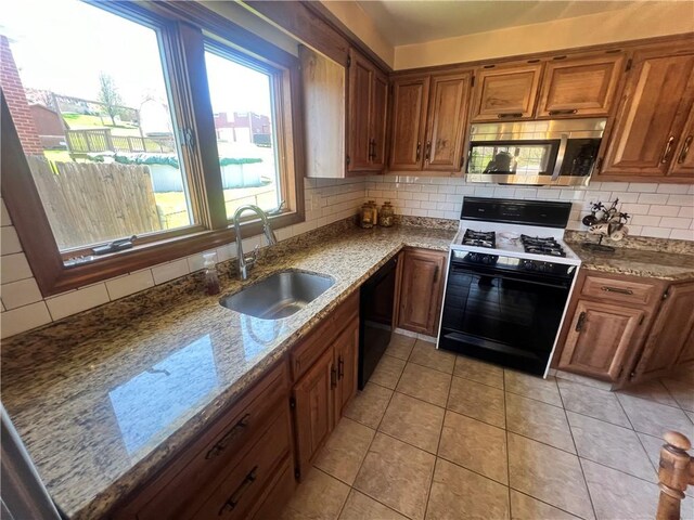 kitchen with stainless steel microwave, backsplash, dishwasher, a sink, and range with gas cooktop