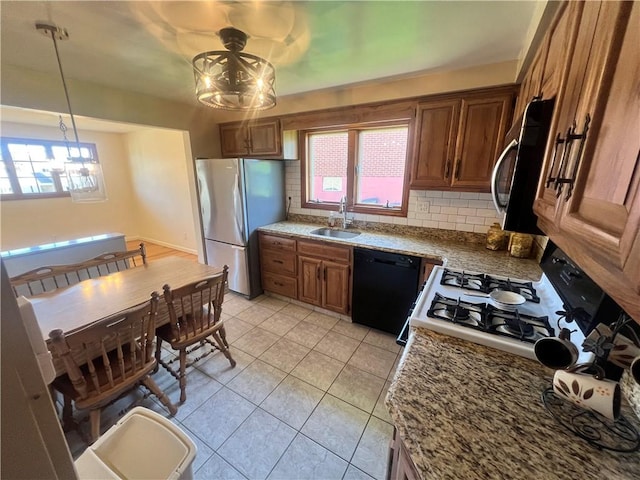 kitchen featuring a sink, an inviting chandelier, stainless steel appliances, brown cabinetry, and backsplash