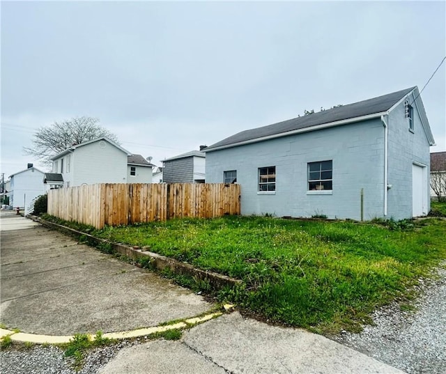 view of home's exterior featuring concrete block siding and fence