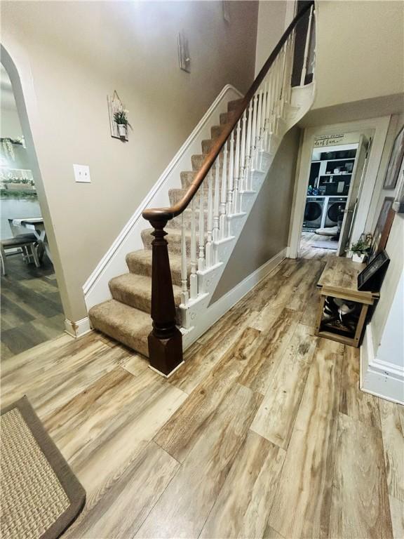 stairway with wood finished floors, arched walkways, and baseboards
