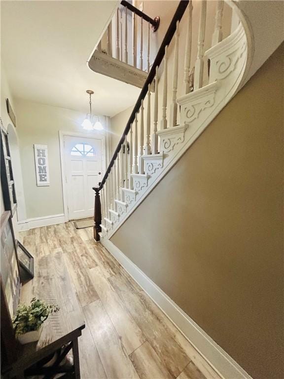 foyer with stairs, a chandelier, wood finished floors, and baseboards